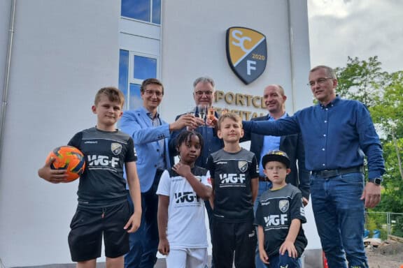 Foto mit Matthias Leuschner, Geschäftsführer WBF-Wirtschaftsbetriebe Freital GmbH (Bauherr), Oberbürgermeister Uwe Rumberg, Henryk Eismann, Geschäftsführer WGF GmbH und Jörg Schneider, Präsident des SCF (v.l.n.r.) mit Nachwuchskickern des SCF beim „Anstoßen“ auf die WGF-Arena. Foto: Stadt Freital