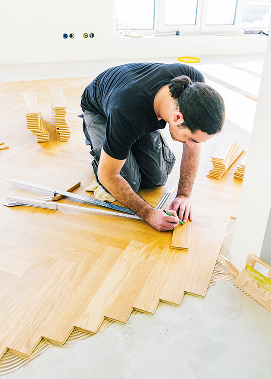 Handwerker verlegt Fußboden, als Symbolbild für bauliche Maßnahmen in der Wohnung. Foto: karepa, AdobeStock Symbolbild für bauliche Maßnahmen auf der Ratgeberseite der WGF: Handwerker verlegt Fußboden. Foto: karepa, AdobeStock